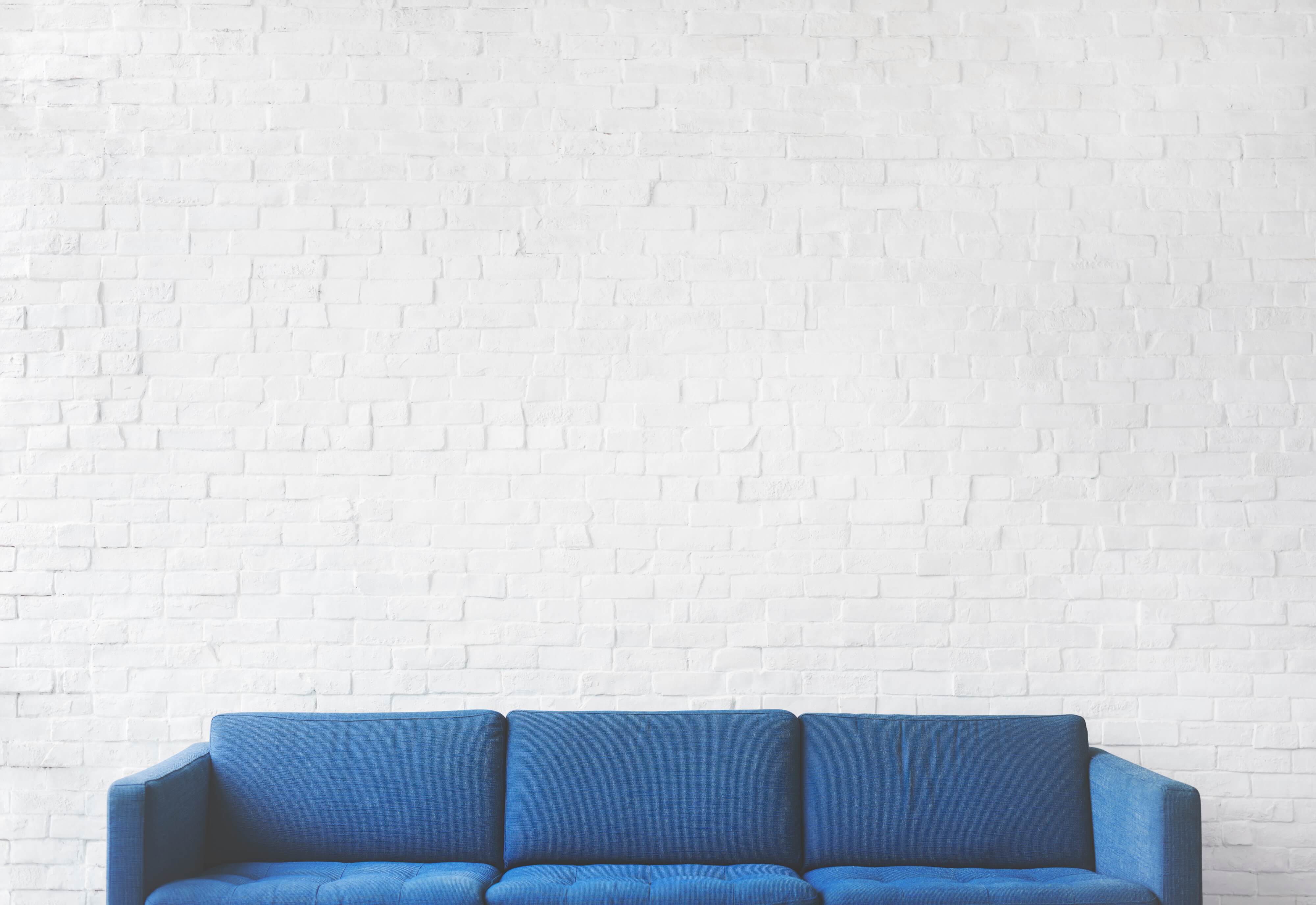 empty blue sofa set against white brick wall